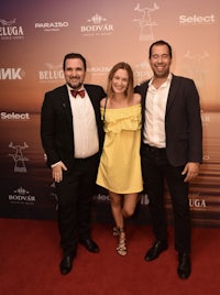 three people posing for a picture on a red carpet