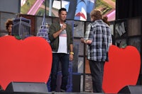 a man is standing on stage with a red apple in front of him