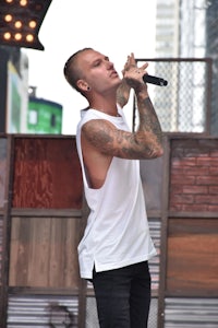 a man in a white tank top singing into a microphone