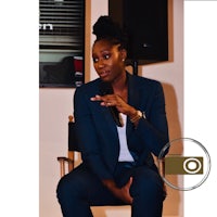 a woman is sitting in a chair and speaking into a microphone