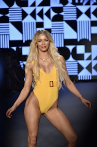 a woman in a yellow swimsuit on the runway