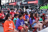 a group of children sitting on chairs in front of a stage