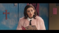 a woman in a pink fur coat holding a book