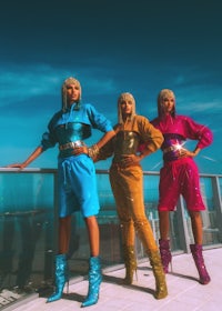 three women in colorful outfits standing on a balcony