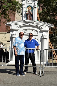 two men posing in front of a statue