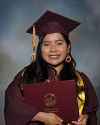 a young woman in a graduation gown holding a diploma