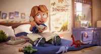 a boy is sitting on a bed with toys and a phone