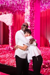 a man and woman hugging in front of a pink flower arrangement