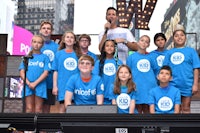 a group of children in blue t - shirts standing on stage