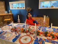 a woman sits at a table with a blue and orange table setting