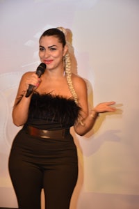 a woman in a black jumpsuit holding a microphone