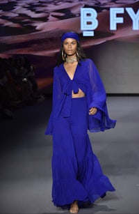 a woman wearing a blue dress on the runway