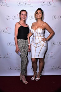 two women standing next to each other on a red carpet