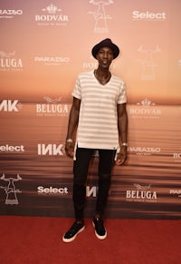 a man in a hat standing on a red carpet