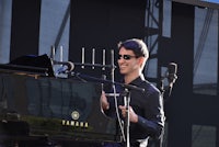 a man in sunglasses playing a piano at a festival