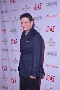 a man in a suit standing on a red carpet