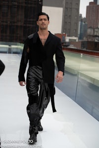 a man in a black suit walking down a runway