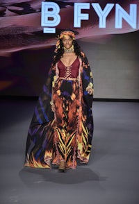 a woman in a colorful dress walks the runway at b fynn fashion week