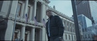 a man in a jacket is standing in front of a building