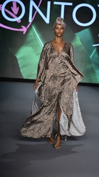 a model walks the runway in a leopard print dress