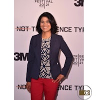 a woman wearing red pants and a blazer standing on a red carpet