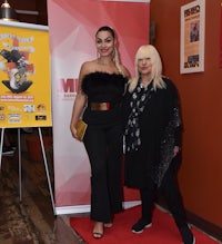 two women standing next to each other on a red carpet