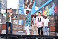 a group of men standing on stage in front of a large sign