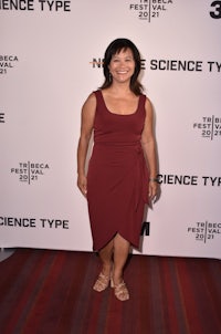 a woman in a maroon dress standing on a red carpet