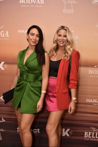 two women posing on a red carpet at an event