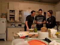 three people standing in a kitchen looking at food