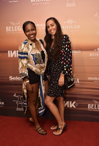 two women posing on a red carpet at an event