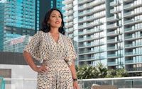 a woman in a patterned dress standing in front of tall buildings