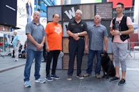 a group of men standing in front of a building with a dog