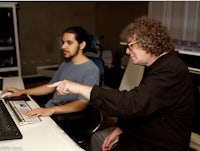 two men sitting in front of a computer