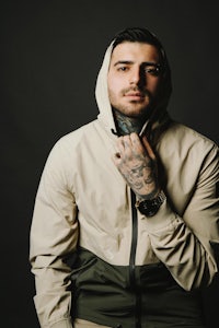 a man in a hoodie with tattoos posing for a photo