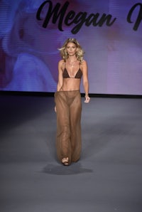 a woman in a brown bikini walking down the runway