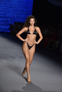 a model walks down the runway in a black bikini