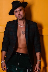 a man in a hat and pants posing against a yellow wall