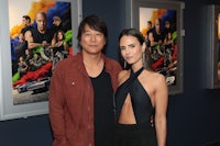 a man and woman posing for a picture in front of posters