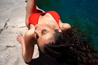 a woman in a red bikini laying next to a pool