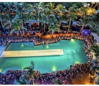 a crowd gathers around a pool at night