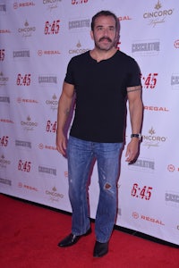 a man in a t - shirt standing on a red carpet