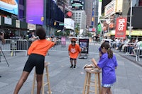 a group of people playing a game of frisbee on a sidewalk in times square