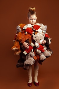 a little girl holding a bunch of stuffed animals