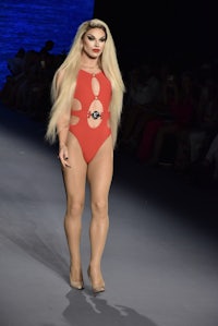 a woman in a red swimsuit walks down the runway