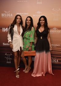 three women posing on a red carpet at an event