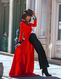 a woman in a red coat leaning against a wall