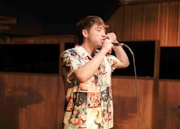 a man in a shirt singing into a microphone