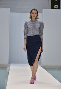 a model walks down a runway in a blue skirt