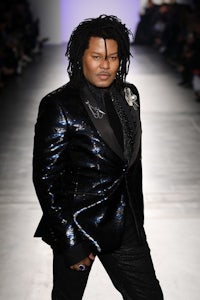 a man with dreadlocks walking down the runway